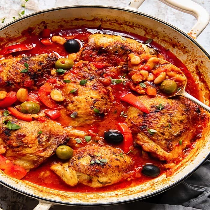 Pan of braised chicken with peppers, olives and herbs